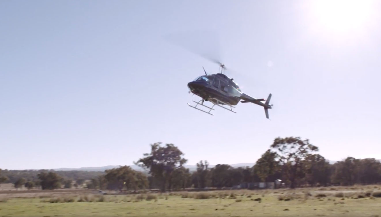 A helicopter lands in a paddock