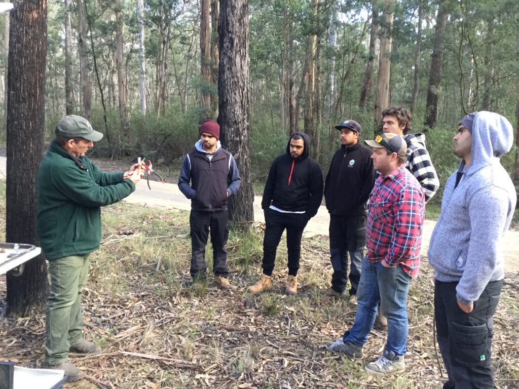 An instructor demonstrates a canid pest ejector to a group of students